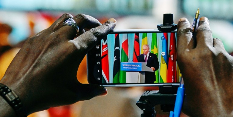Russian President Vladimir Putin is seen on a phone screen as he attends a joint statement with President of Comoros Azali Assoumani at the Russia Africa Summit in St. Petersburg, Russia, Friday, July 28, 2023. (Pavel Bednyakov, Sputnik, Kremlin Pool Photo via AP)