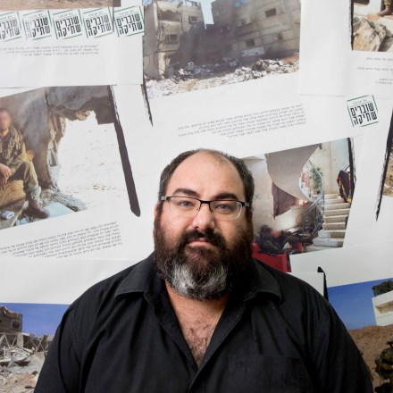 In this photo taken Tuesday, Nov. 21, 2017. Yehuda Shaul, co-founder of "Breaking the Silence" group, poses for photo after a media briefing, in Tel Aviv, Israel. The faces of the soldiers on the background photos were blurred by the organization.  (AP Photo/Oded Balilty)
