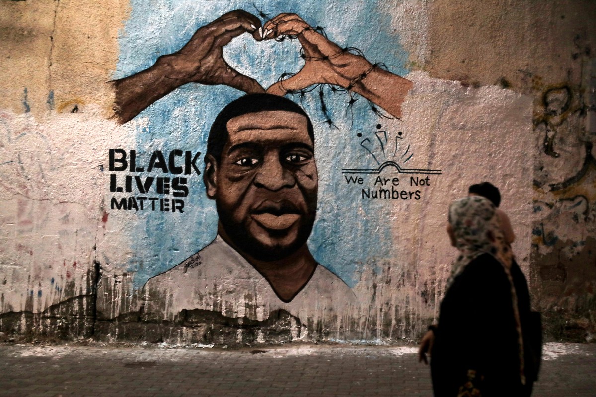 Palestinians walk past a mural of George Floyd, a black American who died after being restrained by police officers, in Gaza City, Tuesday, June 16, 2020.
 (Photo by Majdi Fathi/NurPhoto via Getty Images)