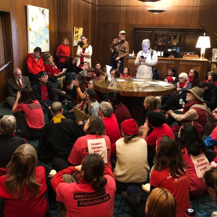 FILE - In this Nov. 21, 2019, file photo, demonstrators against a proposed liquid-natural gas pipeline and export terminal in Oregon sit in in the governor's office in the State Capitol in Salem, Ore., to demand Democratic Gov. Kate Brown stand against the proposal. The Jordan Cove pipeline is undergoing a permitting process and would end at a proposed marine export terminal in Coos Bay, Ore. Members of a federal regulatory agency on Thursday, Feb. 20, 2020, delayed a vote on the project, with one member saying greenhouse gas emissions and endangered species should be considered. (AP Photo/Andrew Selsky, File)