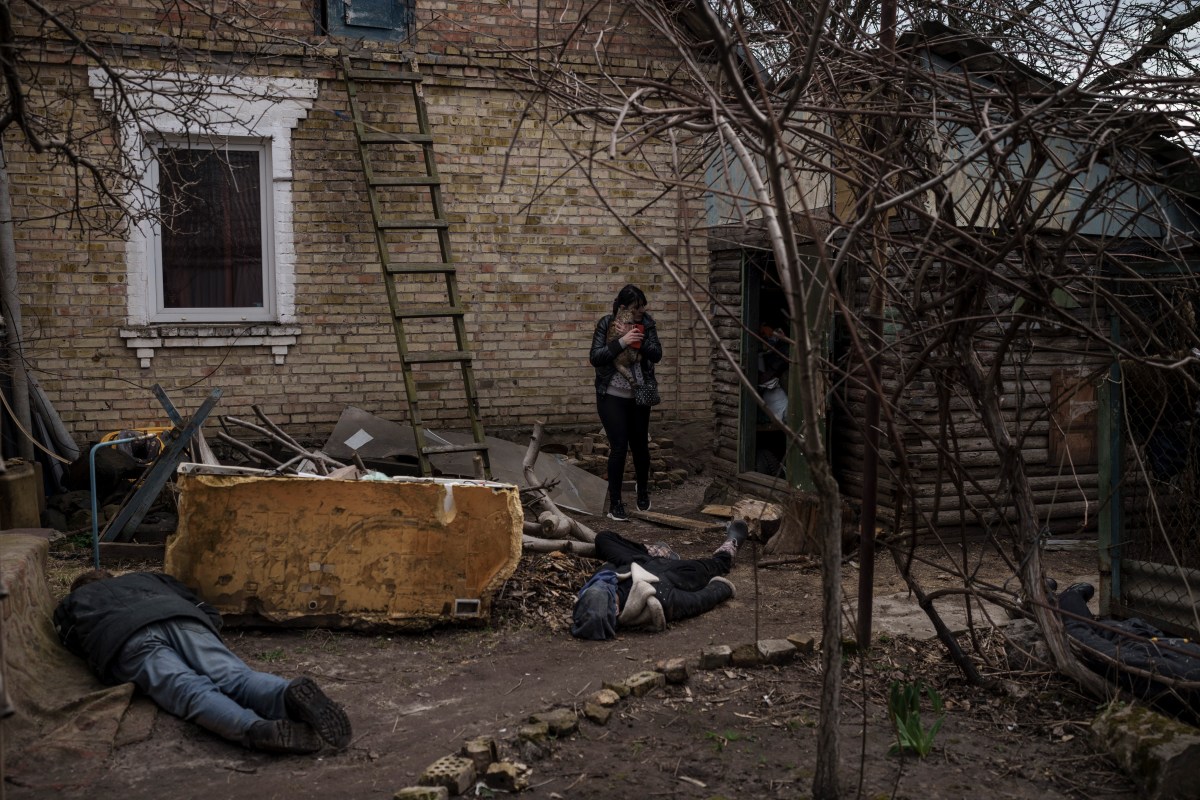 Ira Gavriluk holds her cat as she walks among the bodies of her husband, brother, and another man, who were killed outside her home in Bucha, on the outskirts of Kyiv, Ukraine, Monday, April 4, 2022. Russia is facing a fresh wave of condemnation after evidence emerged of what appeared to be deliberate killings of civilians in Ukraine. (AP Photo/Felipe Dana)