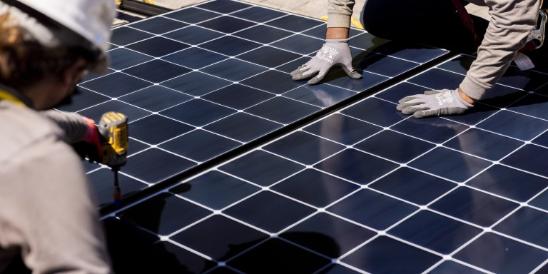 Aoife Murphy, left, and David Strader of Luminalt work to install solar panels on the roof of a home in Menlo Park, Calif., on July 13, 2022. California utility regulators will consider a proposal on Thursday, Dec. 15, 2022, to remake financial incentives for people who install rooftop solar panels on their homes. (Jessica Christian/San Francisco Chronicle via AP, File)