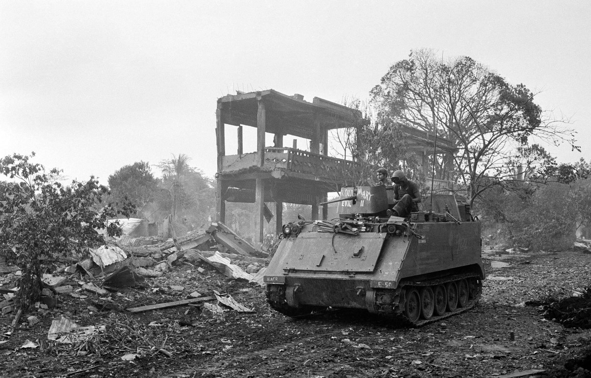 An armored personnel carrier of the U.S. 11th armored regiment rolls past wrecked structures in the ruined town of Snuol, Cambodia Wednesday, May 7, 1970. (AP Photo)