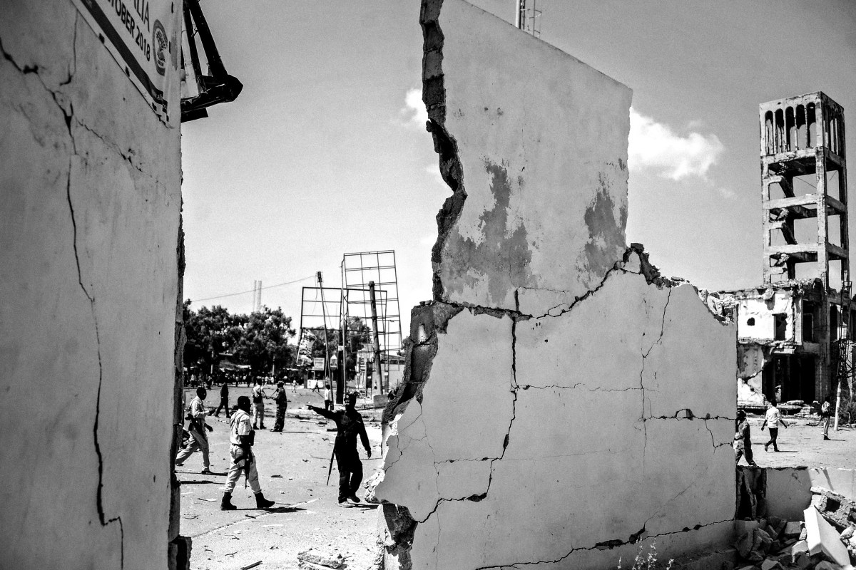 TOPSHOT - People stand next to destroyed walls at the scene of a car bombing attack in Mogadishu, Somalia, on December 22,2018. Seven people were killed  in a double car bomb attack claimed by the jihadist Shabaab group near the presidential palace in the Somali capital Mogadishu, police said. (Photo by Mohamed ABDIWAHAB / AFP) (Photo by MOHAMED ABDIWAHAB/AFP via Getty Images)