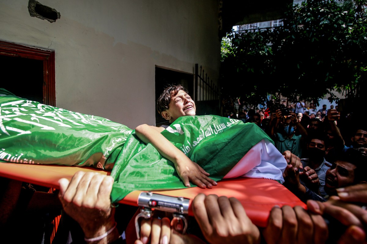 GAZA, PALESTINE - 2021/05/11: (EDITORS NOTE: Image depicts death)A relative mourns while holding the body of Ahmed Al-Shenbari killed in Israeli air raids.Palestinians fired uninterrupted barrages of rockets into Israel, as its military pounded Gaza with air strikes through the early hours of Tuesday, in a dramatic escalation of clashes in Jerusalem. Explosions shook buildings throughout Gaza and rocket sirens sent Israelis in many southern towns scurrying for shelter overnight. Two Palestinians were killed and more than 100 wounded in air strikes, Palestinian officials said. (Photo by Ahmed Zakot/SOPA Images/LightRocket via Getty Images)