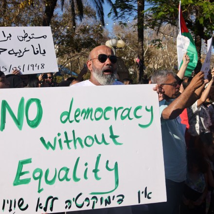 Palestinian and Israeli residents of the coastal city of Jaffa near Tel Aviv, raise placards as they take part in a rally on May 15, 2021, as Palestinians mark the 73rd anniversary of the Nakba, the "catastrophe" of Israel's creation in 1948. - Israeli air strikes pounded the Gaza Strip, killing 10 members of an extended family and demolishing a key media building, while Palestinian militants launched rockets in return amid violence in the West Bank. Israel's air force targeted the 13-floor Jala Tower housing Qatar-based Al-Jazeera television and the Associated Press news agency. (Photo by Ahmad GHARABLI / AFP) (Photo by AHMAD GHARABLI/AFP via Getty Images)