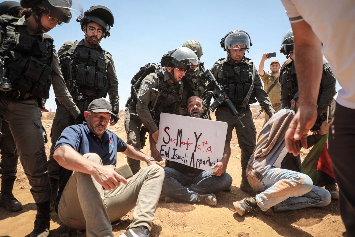 Palestinian demonstrators block the road in front of Israeli soldiers on July 1, 2022, in the Al-Jawaya in Masafer Yatta area  in the Israeli-occupied West Bank that has been at the centre of a protracted legal battle. - The case of Masafer Yatta -- or Firing Zone 918 -- an agriculture area near Hebron in the occupied West Bank, has been one of Israel's longest running legal battles. Palestinian residents of eight villages had been in court for around 20 years fighting Israeli government efforts to evict them. In the early 1980s the army declared the 3,000-hectare (30 square kilometre) territory a restricted military area and claimed it was uninhabited. (Photo by MOSAB SHAWER / AFP) (Photo by MOSAB SHAWER/AFP via Getty Images)