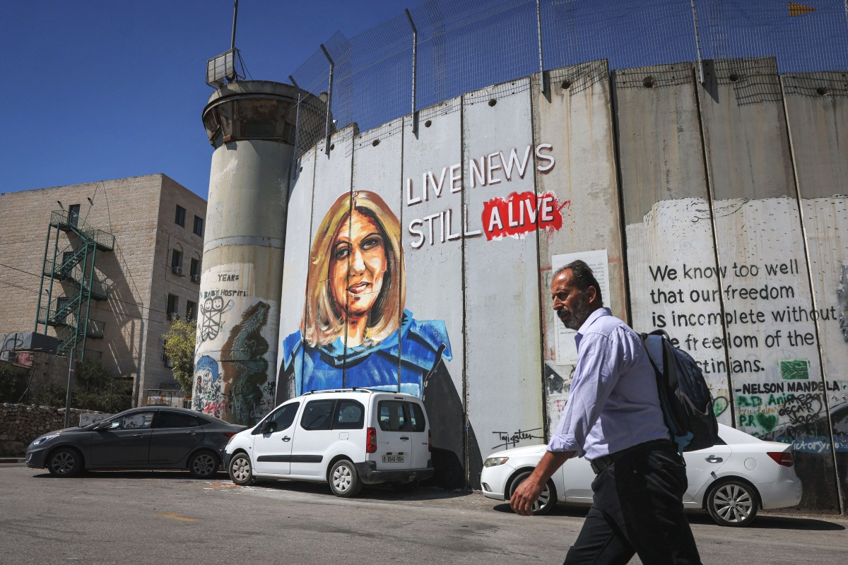 A man walks past a mural depicting slain Al Jazeera journalist Shireen Abu Akleh, who was killed while covering an Israeli army raid in Jenin in May, drawn along Israel's controversial separation barrier in the biblical city of Bethlehem in the occupied West Bank on July 6, 2022. (Photo by AHMAD GHARABLI / AFP) (Photo by AHMAD GHARABLI/AFP via Getty Images)