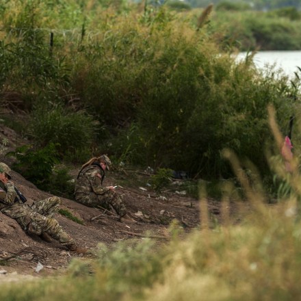 Texas National Guard officers rest along the Rio Grande River at the US southern border with Mexico on October 10, 2022 in Eagle Pass, Texas. - In the 2022 fiscal year US Customs and Border Patrol (CBP) has had over 2 million encounters with migrants at the US-Mexico border, setting a new record in CBP history. (Photo by allison dinner / AFP) (Photo by ALLISON DINNER/AFP via Getty Images)