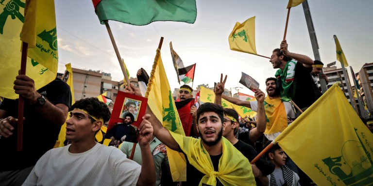 Supporters of the Lebanese Shiite movement Hezbollah wave flags as they watch a televised speech by its leader Hassan Nasrallah (unseen) in the Lebanese capital Beirut's southern suburbs on November 3, 2023. Nasrallah told the United States on November 3, that his Iran-backed group was ready to face its warships and the way to prevent a regional war was to halt the attacks in Gaza. (Photo by Ahmad Al-Rubaye / AFP) (Photo by AHMAD AL-RUBAYE/AFP via Getty Images)