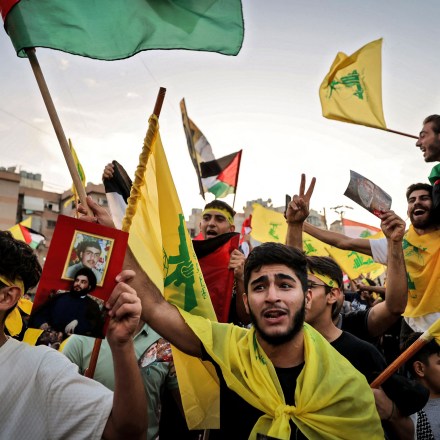 Supporters of the Lebanese Shiite movement Hezbollah wave flags as they watch a televised speech by its leader Hassan Nasrallah (unseen) in the Lebanese capital Beirut's southern suburbs on November 3, 2023. Nasrallah told the United States on November 3, that his Iran-backed group was ready to face its warships and the way to prevent a regional war was to halt the attacks in Gaza. (Photo by Ahmad Al-Rubaye / AFP) (Photo by AHMAD AL-RUBAYE/AFP via Getty Images)