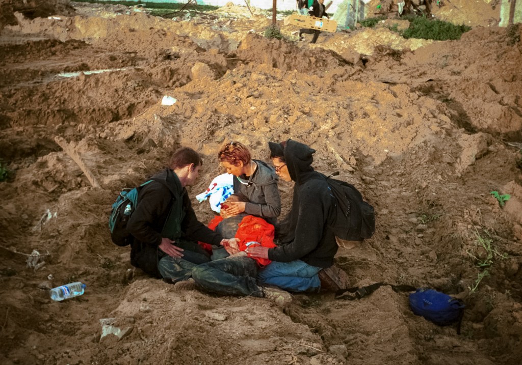 RAFAH REFUGEE CAMP, GAZA STRIP - MARCH 16:  American peace activist Rachel Corrie lies bleeding while being helped by colleagues after she was run over by an Israeli bulldozer March 16, 2003 in the Rafah refugee camp in the Gaza strip. Corrie was killed by an Israeli bulldozer when she tried to stop it from destroying a Palestinian house in the Rafah refugee camp. Corrie was a member of the International Solidarity Movement.  (Photo by International Solidarity Movement/Getty Images)