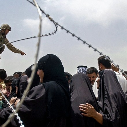 A US marine points as he tells a crowd of men and women to move the line back outside the Abu Ghraib prison 12 May 2004. Hundreds of Iraqis crowd everyday outside the detention center in an effort to find news about their loved ones and to hopefully get an appointment slip for the near future to visit them.  AFP PHOTO/Roberto SCHMIDT / AFP / ROBERTO SCHMIDT        (Photo credit should read ROBERTO SCHMIDT/AFP via Getty Images)