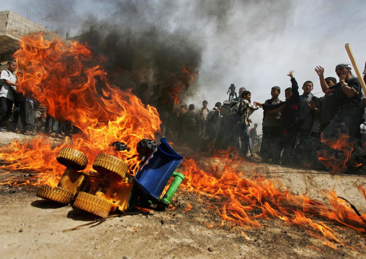 GAZA CITY, GAZA STRIP - APRIL 13: Child members of The Mini Palestinian Parliament burn toy bulldozers as a symbol of the D9 Bulldozers made by Caterpillar Company (CAT) and supplied to the Israeli military, during a rally to commemorate the death of Rachel Corrie, April 13, 2005 in Rafah refugee camp in the southern Gaza Strip. Rachel Corrie, a U.S. volunteer with the International Solidarity Movement was killed by an Israel military bulldozer in Rafah two years ago on March 16, 2003 when she tried to prevent the demolition of a Palestinian home and during the rally the Palestinian children demanded that the Caterpillar Company (CAT) stopped the sales of the bulldozers to the Israeli army.  (Photo by Abid Katib/Getty Images)